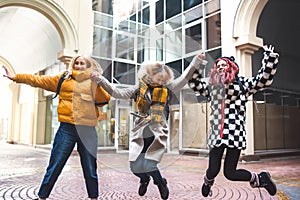 Friends teenagers students with school backpacks, having fun on the way from school and jump. the City background