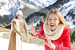 Friends throwing snowballs in a snowy mountain in winter photo