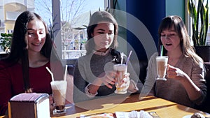 Friends toasting, joyful girls with milkshakes rest in cafe on weekends