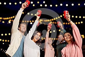 Friends toasting party cups on rooftop at night