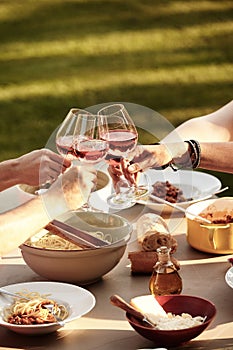 Friends toasting with wine over a spaghetti meal