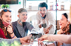 Friends toasting wine at restaurant wearing face masks - New normal lifestyle concept with happy people having fun together