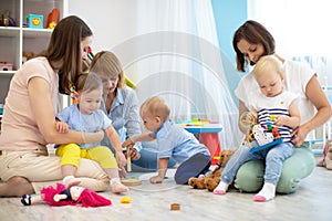 Friends with toddlers playing on the floor in play room