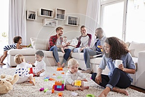 Friends with toddlers playing on the floor in sitting room