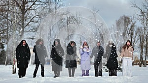 Friends toss snow from their hands.