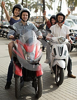 friends of tourists of different generations enjoy a ride on electric scooters