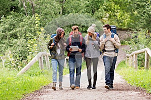 Friends or travelers hiking with backpacks and map