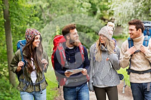 Friends or travelers hiking with backpacks and map