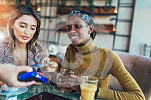 Friends using credit card and making contactless payment in a restaurant