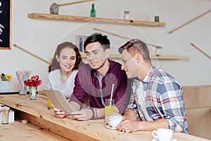 Friends using digital tablet in cafe