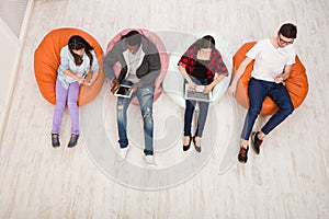 Friends using gadgets, sitting indoors in line