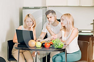 Friends using laptop in kitchen