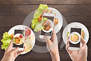 Friends using smartphones to take photos of sausage, pork chop,