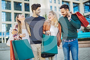 Friends walking along street with shopping bags