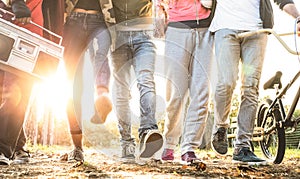 Friends walking in city park with backlight and sunflare halo - Millenial friendship concept and multiracial young people on