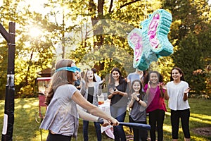 Friends watch pre-teen girl hitting a piï¿½ata on her birthday