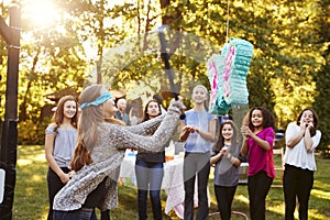 Friends watch teenage girl hitting a piï¿½ata on her birthday