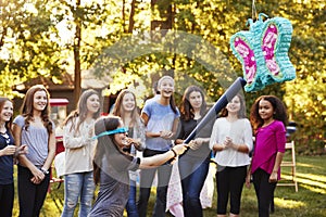 Friends watch a young girl hitting a piï¿½ata on her birthday