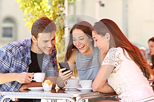 Amigos seguimiento los medios de comunicación en elegante teléfono en café la tienda 