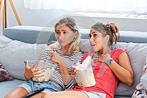 Two sentimental women friends upset crying and wiping tears with handkerchiefs while watching dramatic, sad movie, TV reality show