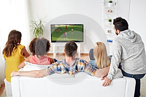 Friends watching soccer game on tv at home