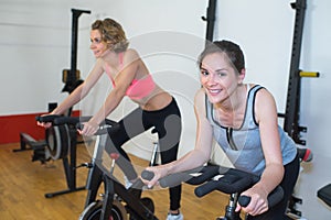 Friends working out cycling in modern fitness club