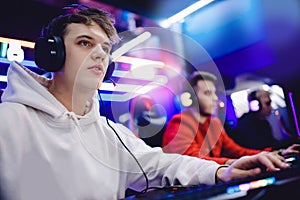 Friends young guys play online video games with headphones in an internet club cafe. Esports team concept