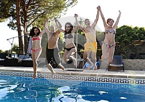 Friends young happy attractive men women in bikini jumping in the air to hotel swimming pool