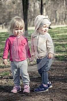 Friendship between children girls holding together with hands in summer park symbolizing children friendship and childhood