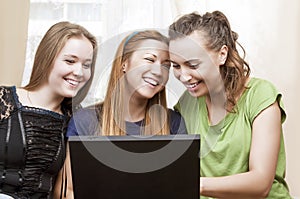 Friendship Concepts: Three Laughing Caucasian Girls Using Laptop