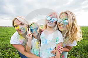 Friendship, holidays, color concept - friends smiling and having fun in colors on the festival of holi