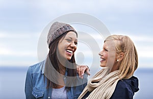 Friendship and laughter can brighten any day. Two happy young women smiling on the beach.