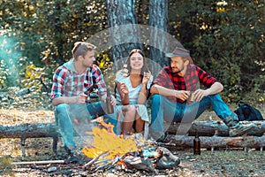 Friendship and leisure concept. Friends hikers watching fire together on camp. Weekend. Good day for spring picnic in