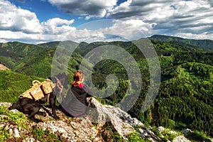 Friendship between man and dog. Girl with big dog Bandog sitting on top of the hill and looking on beautiful nature