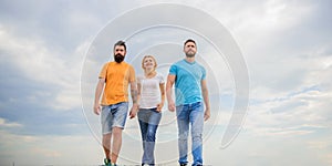 Friendship tested for years. United threesome true friends. Men and woman walks dramatic cloudy sky background. True