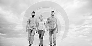 Friendship tested for years. United threesome true friends. Men and woman walks dramatic cloudy sky background. True