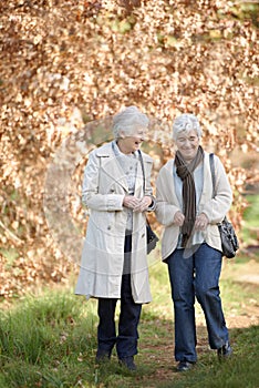 Friendship in their autumn years. Two senior women out for a nature walk.
