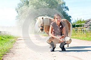 Friendship and trusting. Smiling teenage girl with little shetland pony.