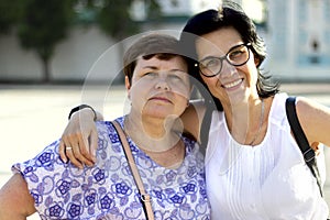 The friendship of two adult women lasts for a very long time Happy friends hug and hold each other, smile. Women travel