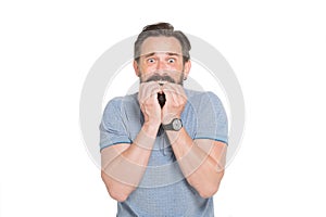 Frightened bearded man biting his nails while being nervous