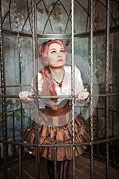 Frightened beautiful steampunk woman in the cage