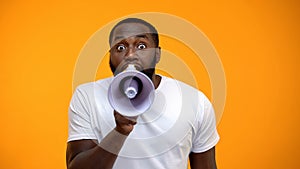 Frightened black man screaming in megaphone, spreading information, awareness