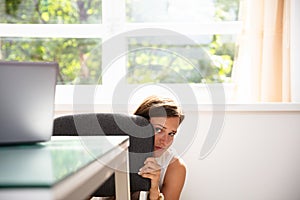 Frightened Businesswoman Hiding Behind Chair