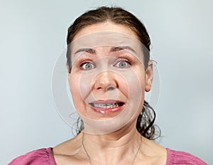 Frightened and confused Caucasian woman, portrait on grey background, emotions series