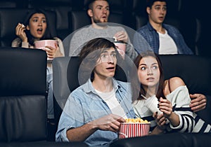 Frightened couple watching thriller on night out in cinema