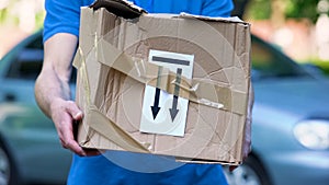 Frightened delivery worker giving broken customer parcel, shipment accident