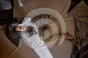 Frightened depressed ginger redhead woman lying alone on bed