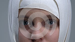 Frightened girl in headwrap looking at camera, violence victim, close-up