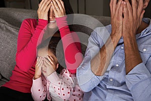 Frightened Hispanic Family Sitting On Sofa And Watching TV