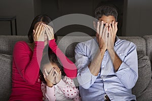 Frightened Hispanic Family Sitting On Sofa And Watching TV